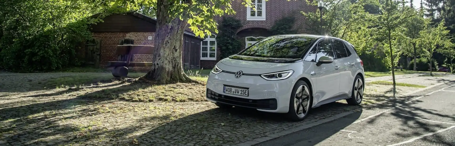 Ein weißer VW ID. 3 im Schatten eines Baumes. 